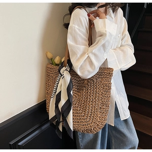 Detail of hand-woven straw tote bag with black and white scarf and faux leather straps