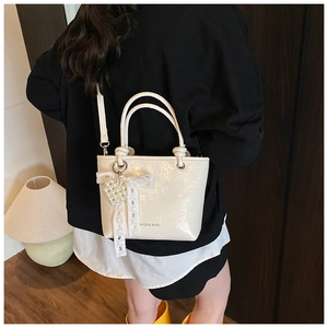Chic beige glossy bucket bag with pearl heart charm and lace bow detail for women