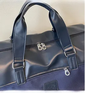 Detail of navy canvas travel bag featuring smooth metal zippers and leather patchwork
