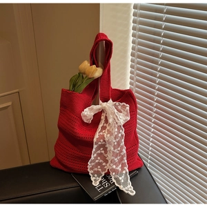 Détail du sac cabas en tricot ajouré rouge avec nœud en dentelle blanche et texture tissée