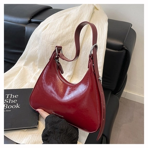 Detail of burgundy glossy leather baguette bag with silver hardware and adjustable strap