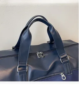 Detail of durable dark blue travel bag featuring reinforced wide handles and dual zippers