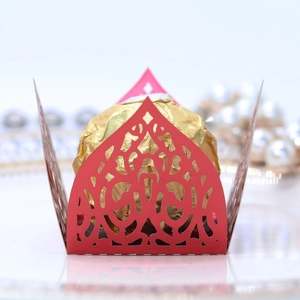 Macro detail of red laser-cut vine pattern candy box holding a gold foil chocolate