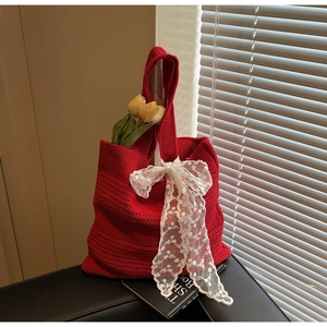 Détail du sac cabas rouge en tricot avec nœud en dentelle blanche et motif crochet