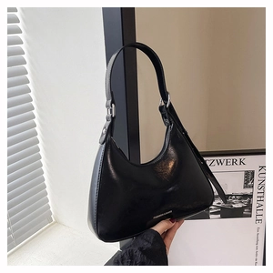 Detail of a black glossy leather hobo bag with Fashion & Bags logo held by hand