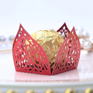Close-up of red laser-cut candy box with floral patterns and a chocolate inside