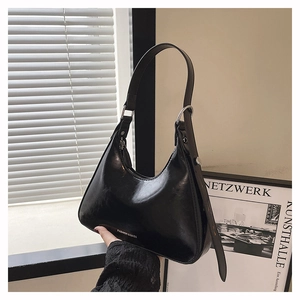 Detail of black glossy PU leather underarm bag with silver buckle and fashion text logo