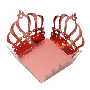 Macro shot of laser-cut crown cupcake wrapper in metallic red with heart hollow details