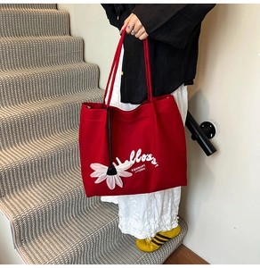 Detail of red canvas tote bag with Hells text and 3D white flower charm on stairs