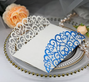 Detail of laser-cut wedding invitation cover with blue glitter scrollwork patterns