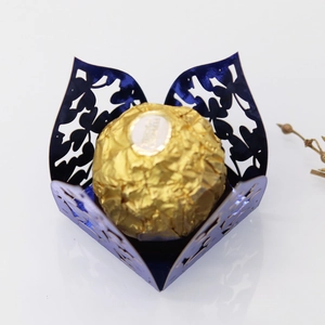 Macro detail of dark blue laser-cut clover candy box with hollow floral patterns