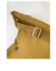 Détail du sac en nylon jaune moutarde montrant la texture ripstop et le logo argenté
