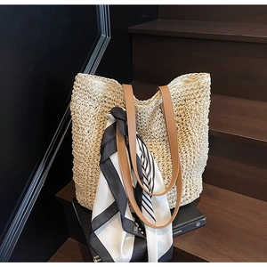 Detail of beige woven straw tote bag with brown PU straps and striped silk scarf decoration