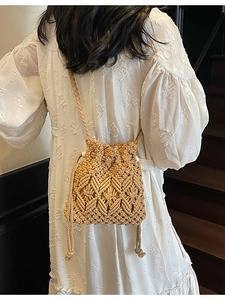 Bohemian woven straw bucket bag with drawstring closure and crossbody strap for beach vacation