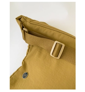 Détail d'un sac en nylon ripstop jaune moutarde avec sangle et logo métallique