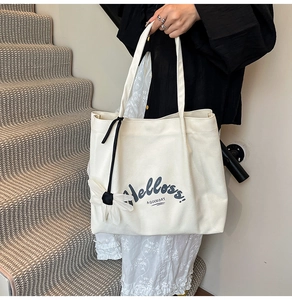 Detailed macro view of off-white canvas tote bag featuring black artistic lettering