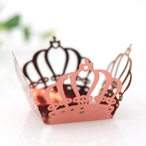 Detail of laser-cut crown paper cupcake wrappers in elegant rose gold for party decor