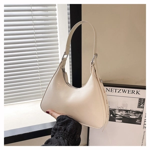 Detail of minimalist cream leather crescent shoulder bag with silver hardware and branding