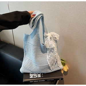 Détail d'un sac cabas en maille ajourée bleu clair avec un nœud décoratif en dentelle