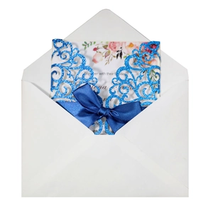 Close-up of laser cut glitter wedding invitation with blue satin ribbon and floral insert