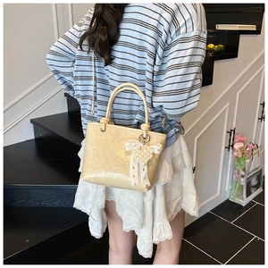 Detail of beige faux leather bucket bag with pearl heart charm and lace bow decor