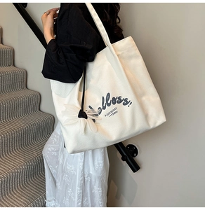 Detail of white canvas tote bag with black text and mesh floral petal pendant decoration