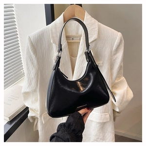 Detail view of the black crescent underarm bag with polished finish and logo