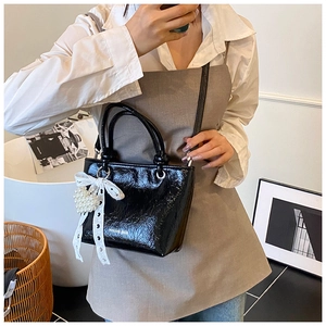 Black crinkled patent leather bucket bag with lace bow and pearl heart charm detail