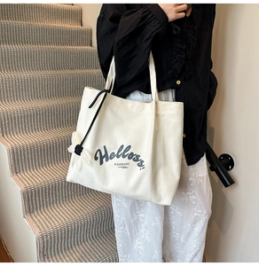 Detail of canvas tote bag with Helloss print and flower charm on interior stairs