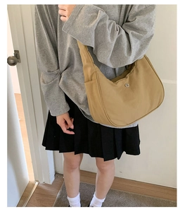 Gros plan sur le sac croissant kaki avec logo en métal et poche latérale à étages