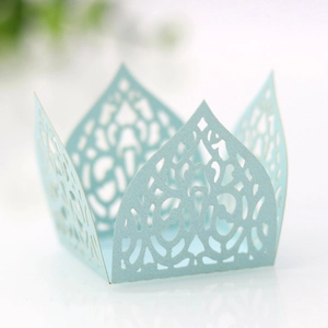 Macro shot of light blue laser-cut cupcake wrappers with crown and filigree design