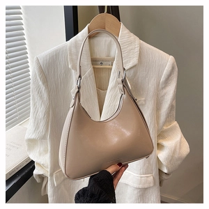 Detail of beige crescent hobo bag made of smooth faux leather with metal ring hardware