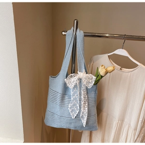 Gros plan sur un sac cabas ajouré bleu clair avec un nœud en dentelle blanche et tulipe