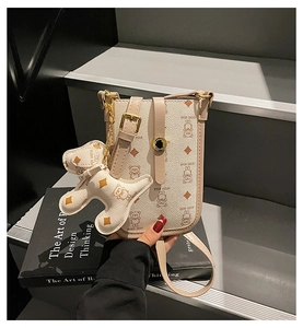 Detailed close-up of a beige crossbody bag with KEDDY BEAR print and dog-shaped charm