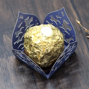 Detaillierte Laserschnitt-Kleemuster auf dunkelblauer Geschenkbox mit goldener Praline