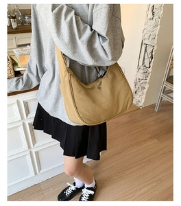 Vue détaillée du sac à bandoulière en nylon kaki avec un logo en métal rond discret