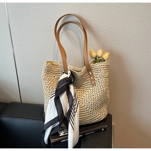Detailed texture of beige straw tote bag with brown PU handles and striped silk scarf