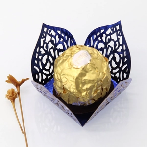 Detail showing dark blue laser-cut paper chocolate box with elegant floral hollow pattern