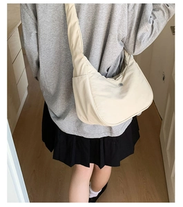 Détail du sac à bandoulière croissant en nylon crème montrant sa forme demi-lune minimaliste