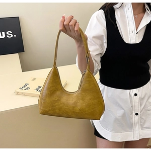 Detail of mustard yellow hobo bag with crocodile embossed texture and silver hardware