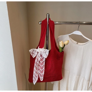 Détail du sac cabas rouge tricoté avec nœud en dentelle blanche et motif ajouré