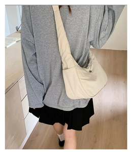 Détail du sac à bandoulière en nylon beige montrant la texture et la poche latérale