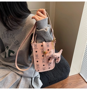 Detail of pink mini crossbody bag with teddy bear pattern and matching dog charm