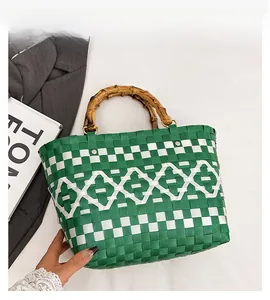 Détail d'un sac seau tressé avec motifs vert et blanc et poignées en bambou naturel