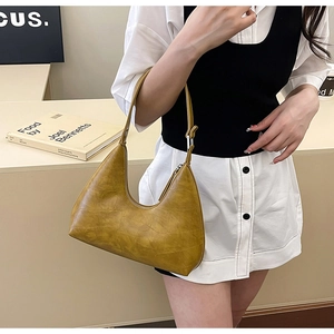 Detail of yellow crocodile embossed half-moon hobo bag with adjustable strap and zipper