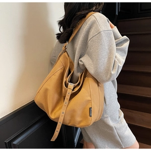 Close-up of adjustable strap with metal eyelets and logo label on caramel canvas hobo bag