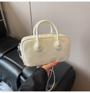 Detail shot of cream Boston bag featuring embossed logo and leather chain strap