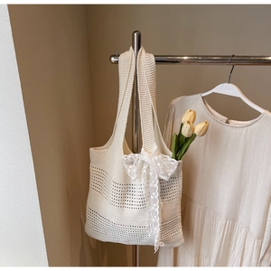 Détail d'un sac cabas en tricot ajouré avec nœud en dentelle blanche et accents de tulipe
