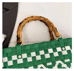 Détail du sac tressé vert et blanc avec poignées en bambou naturel et anneaux en D dorés