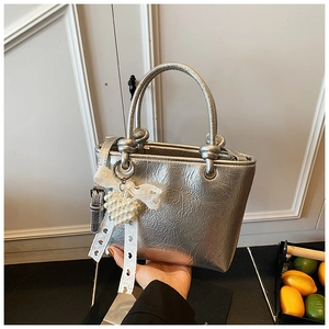 Detail of silver metallic bucket bag with pleated texture and pearl heart charm